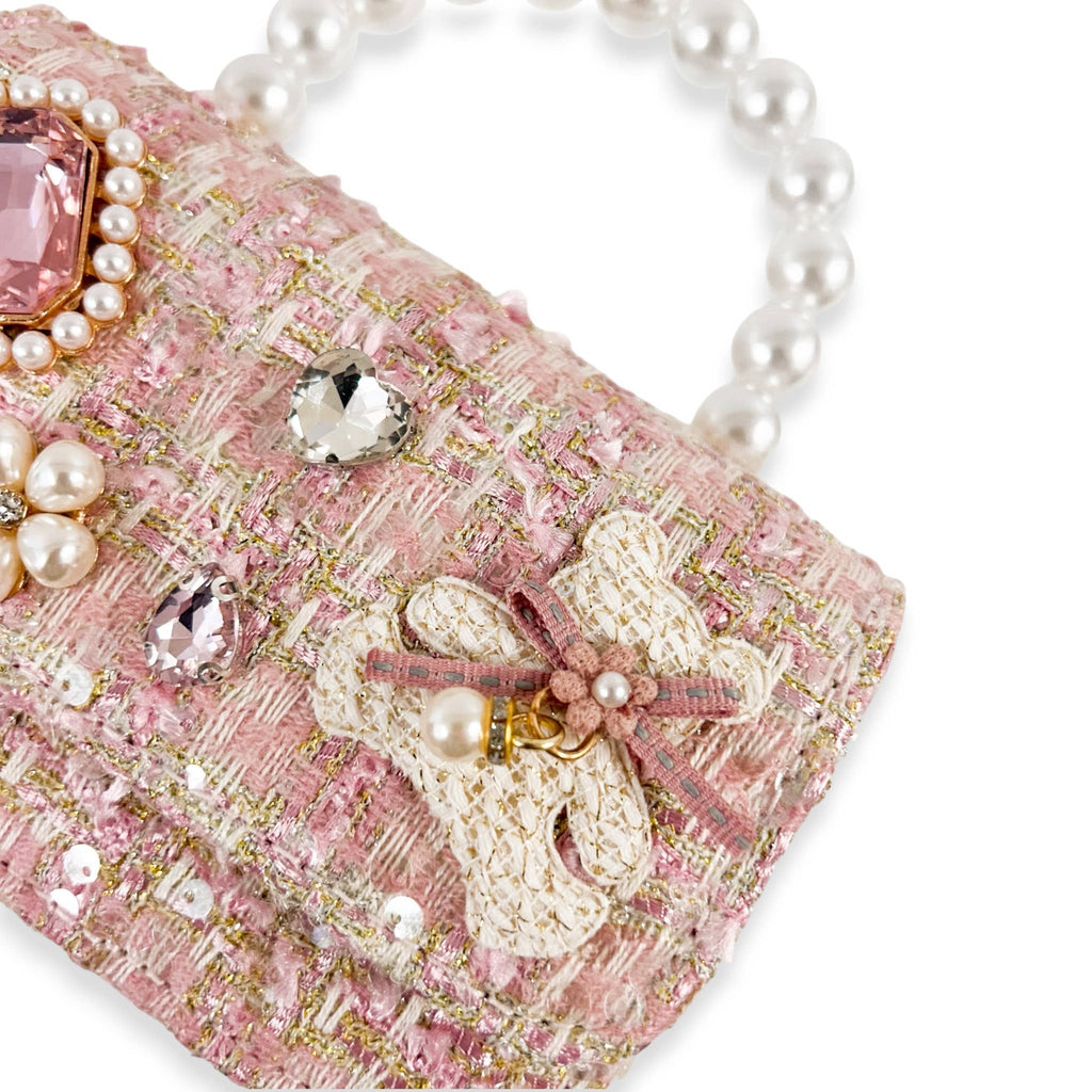 Pink handbag with pearl embellishments on a white background