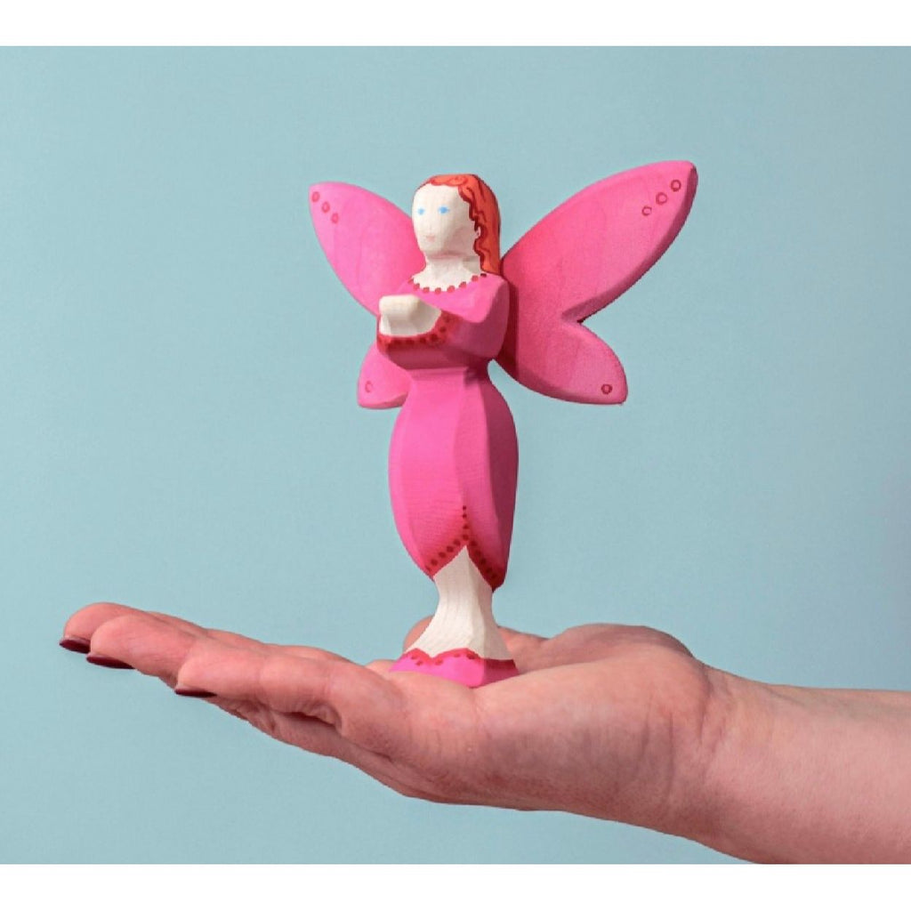 Pink fairy figurine with red hair on a light blue background
