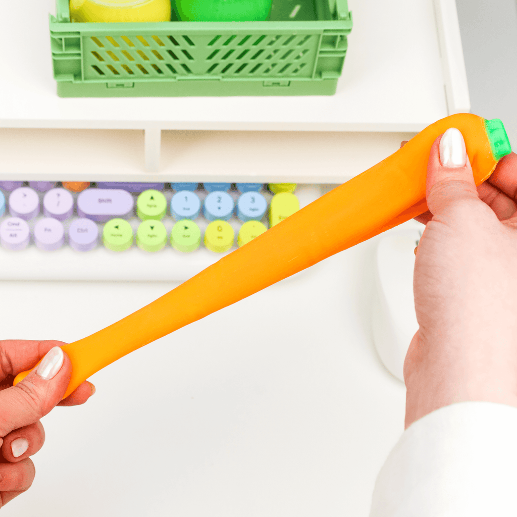 An orange carrot-shaped eraser with a green top, shown diagonally on a plain white background.