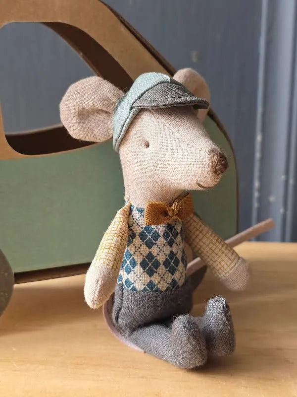 A plush toy mouse dressed in vintage clothing, featuring a teal cap, argyle vest, brown bow tie, and gray trousers, set against a solid beige background.