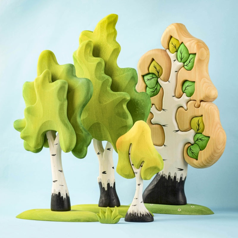 Colorful tree-shaped objects on a wooden surface with a light blue background