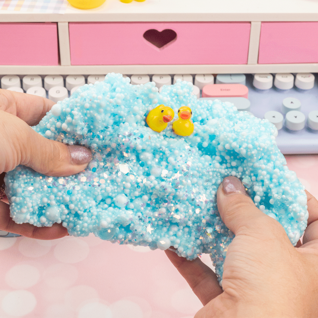 Kawaii Slime Company Squeaky Clean Bubble Bath in a round light blue container with a clear dome lid, featuring a yellow rubber duck, smaller yellow duck figures, clear bubble balls, and a large white ribbon bow on the front.