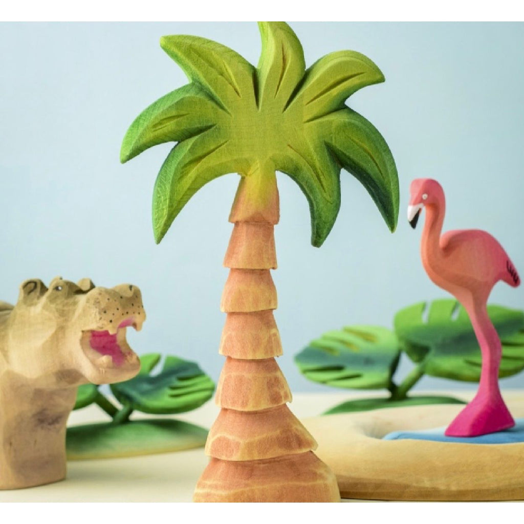 Wooden palm tree figurine on a wooden surface with a light blue background