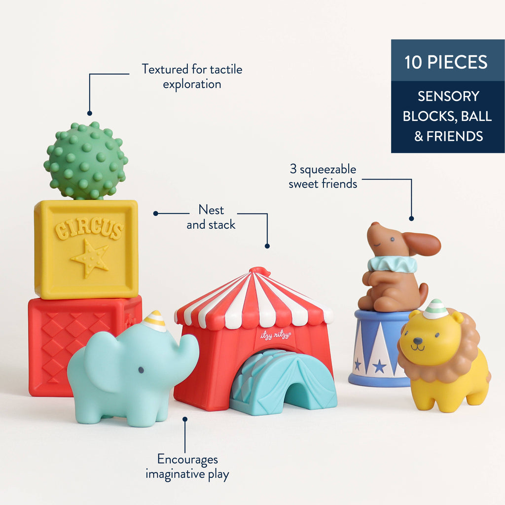 A set of colorful baby bath toys shaped like circus-themed objects, including a green spiky block labeled CIRCUS, a yellow block, a red block, a light blue elephant, a red and white striped tent, a blue and white striped bucket with a brown dog figure, and a yellow lion figure, all on a white background.