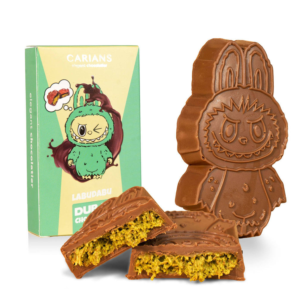 Chocolate rabbit-shaped cookie on a white plate with a green and yellow box labeled 'Dubai Chocolate' featuring a cartoon character.