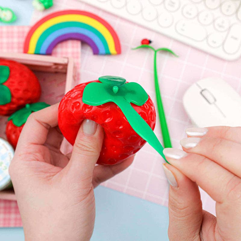 Red strawberry-shaped sensory toy with green top on a white background