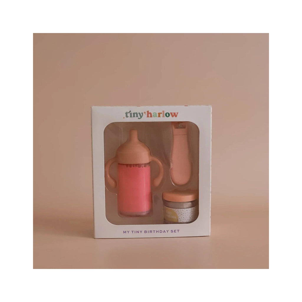 Pink sippy cup, jar with spoon, and colorful sprinkles on a beige background