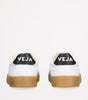 White sneaker with black logo and brown sole on a white background