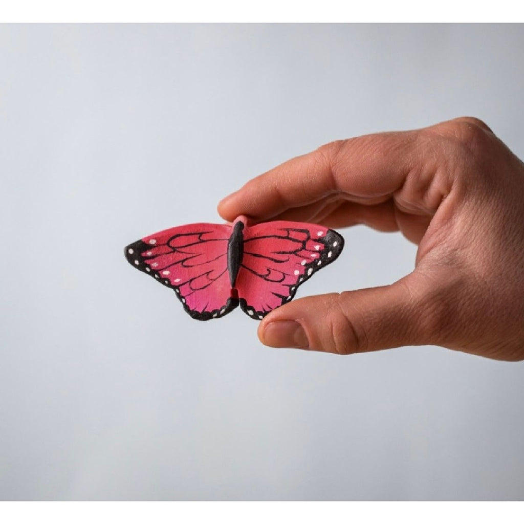 Pink butterfly toy with black accents on a wooden surface