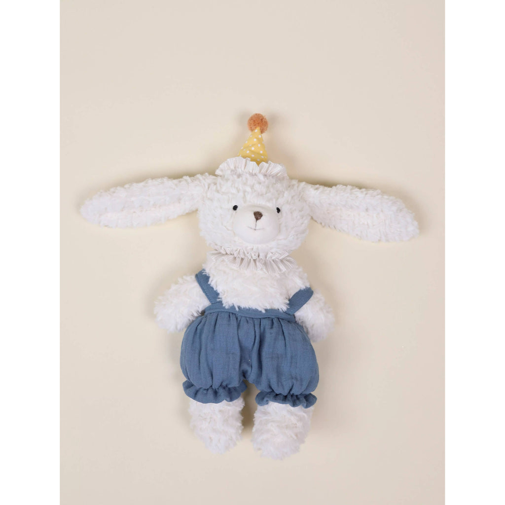 Plush toy rabbit wearing a party hat on a beige background