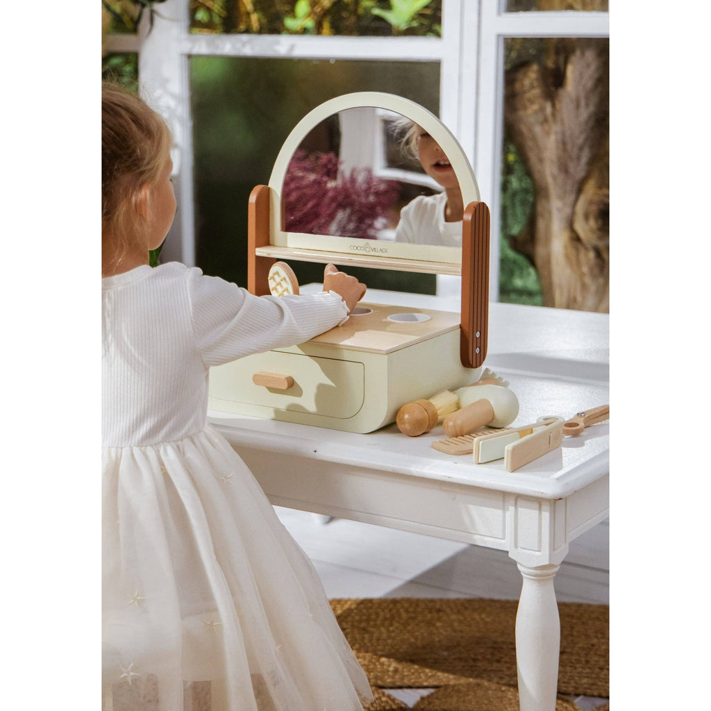 Wooden vanity set with mirror, brushes, and other tools on a beige background