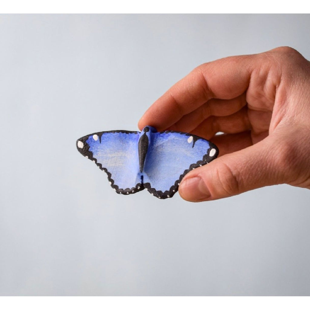 Blue butterfly-shaped object on a wooden surface with a light blue background