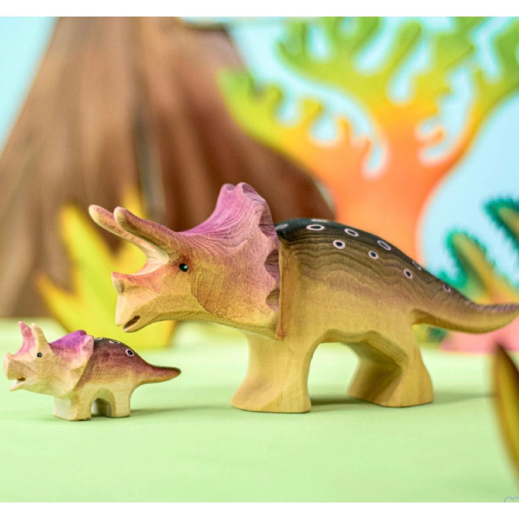 Wooden triceratops dinosaur toys on a wooden surface with a light blue background