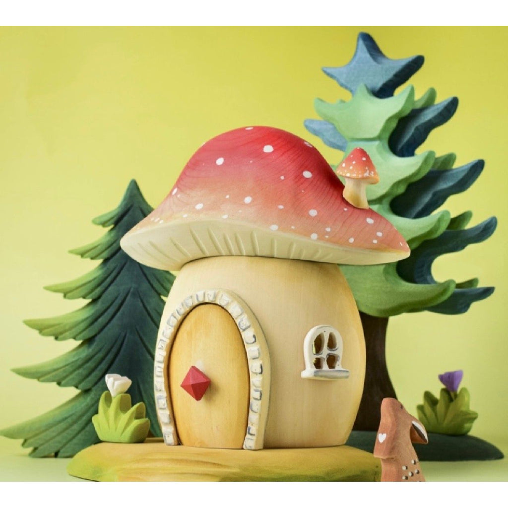 Fairy house with a red mushroom roof on a wooden surface
