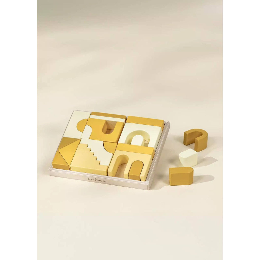 Set of geometric wooden building blocks in a clear box on a beige background