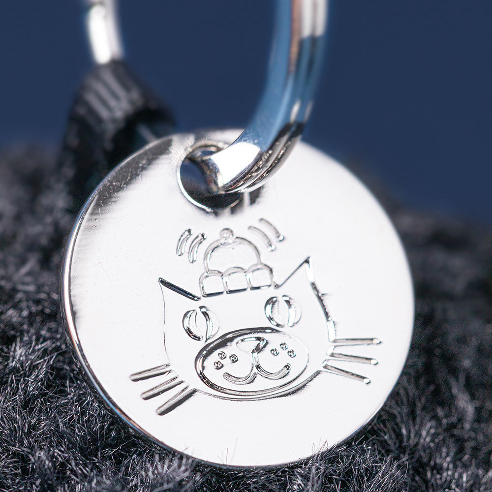 Black plush keychain with a smiling face on a white background