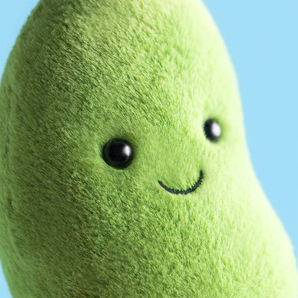 Green plush toy with a smiling face on a white background