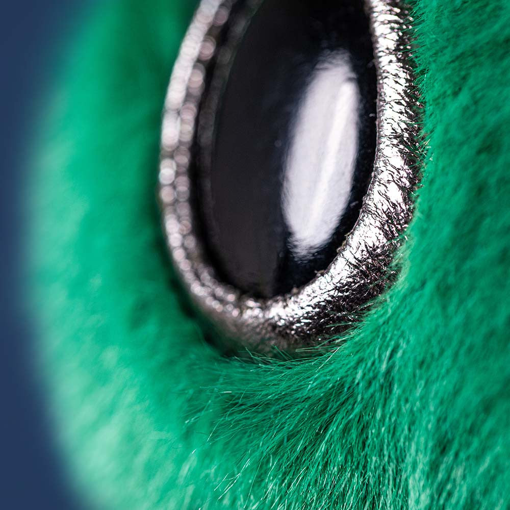 Green alien plush toy with black eyes on a white background