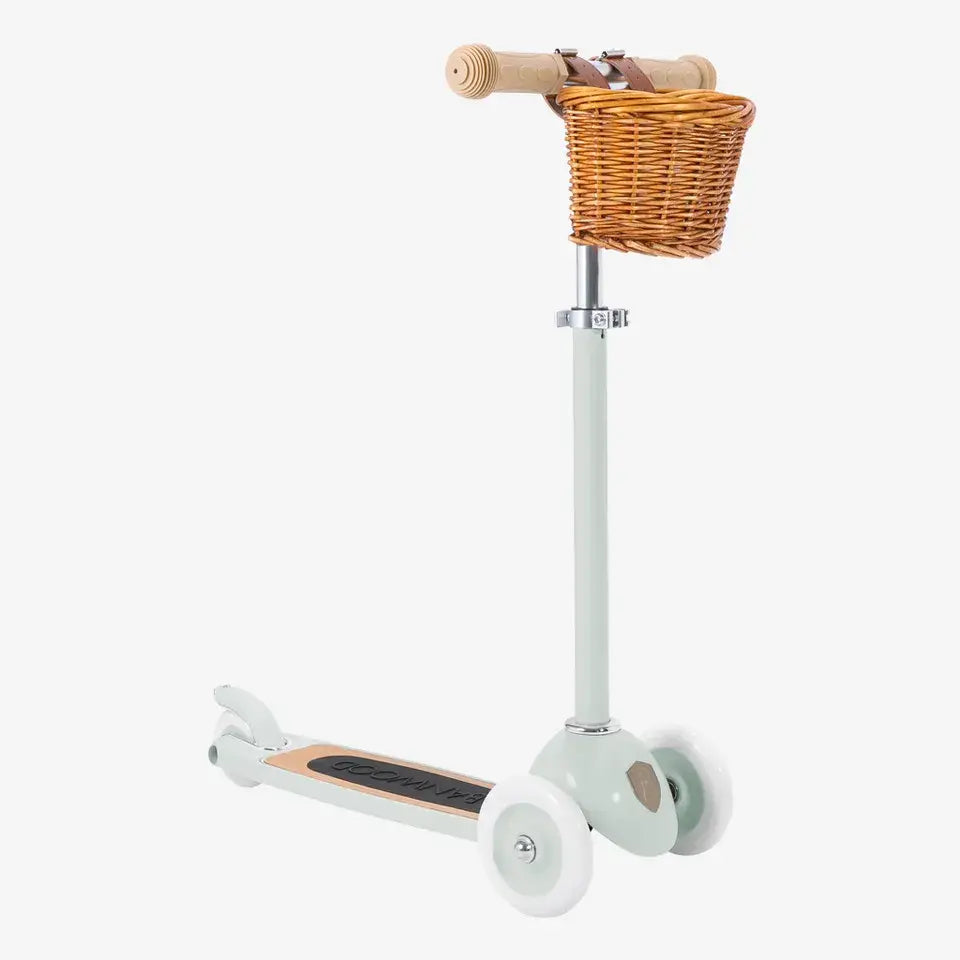 A three-wheeled scooter in pale mint color with a wicker basket, featuring a T-handlebar and rubber grips.