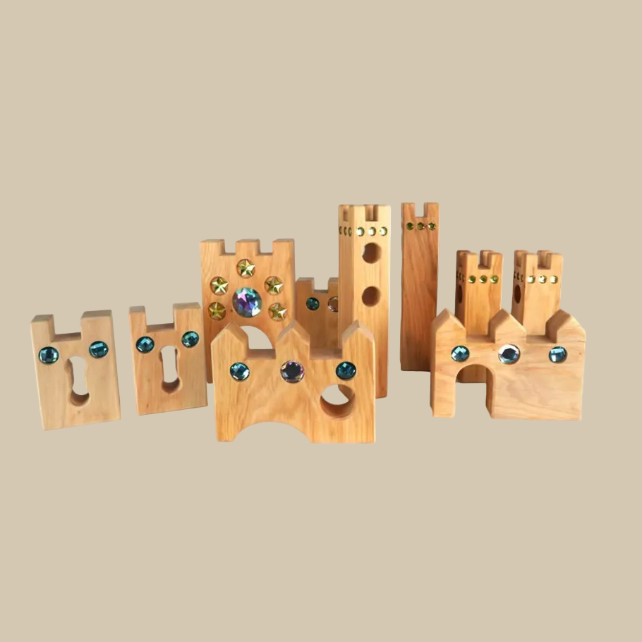 A wooden castle toy with gold-colored studs and faux gemstones in blue, white, and green, set against a plain white background.
