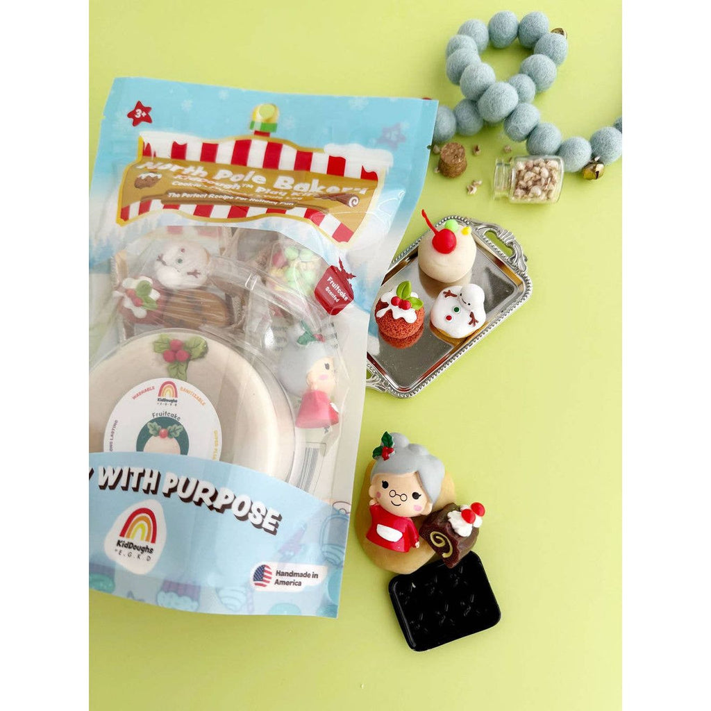 8oz Split White and Tan Dough with a holly charm, Mrs. Claus figure, silver tray, assorted desserts, small cookie tray, cloche, cherries, jar of fruitcake mix, jar of nuts, and a recipe list