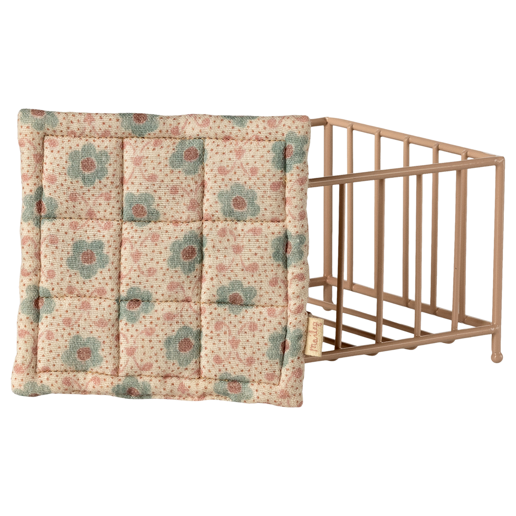 Beige crib with floral mattress on a white background