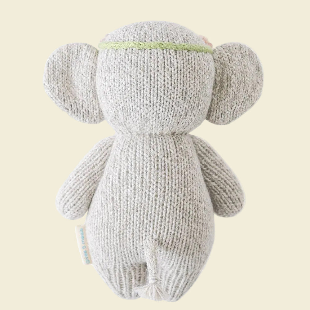 Knitted elephant toy with a floral headband on a white background
