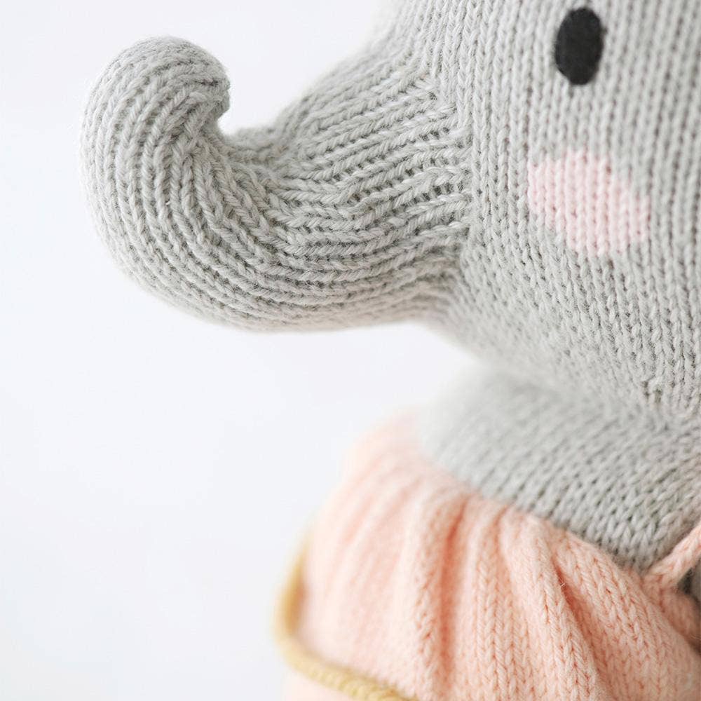 Close-up of a knitted item with a pink bow and gradient colors.