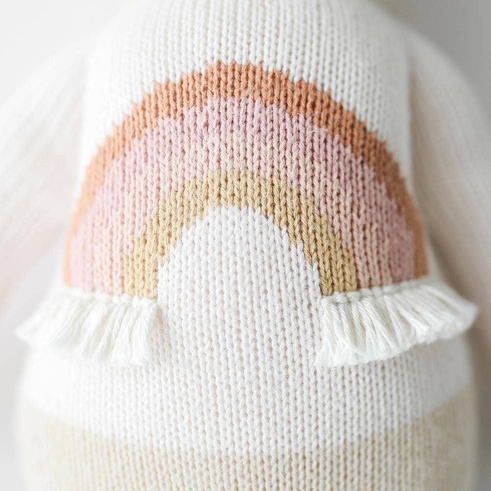 Newborn baby wrapped in a swaddle with a unicorn toy on a textured blanket
