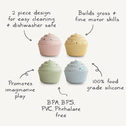 Four cupcake-shaped containers in pink, beige, green, and blue with sprinkles on a white background.
