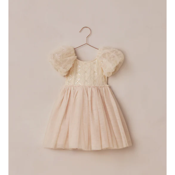 Beige dress with puff sleeves on a hanger against a beige wall