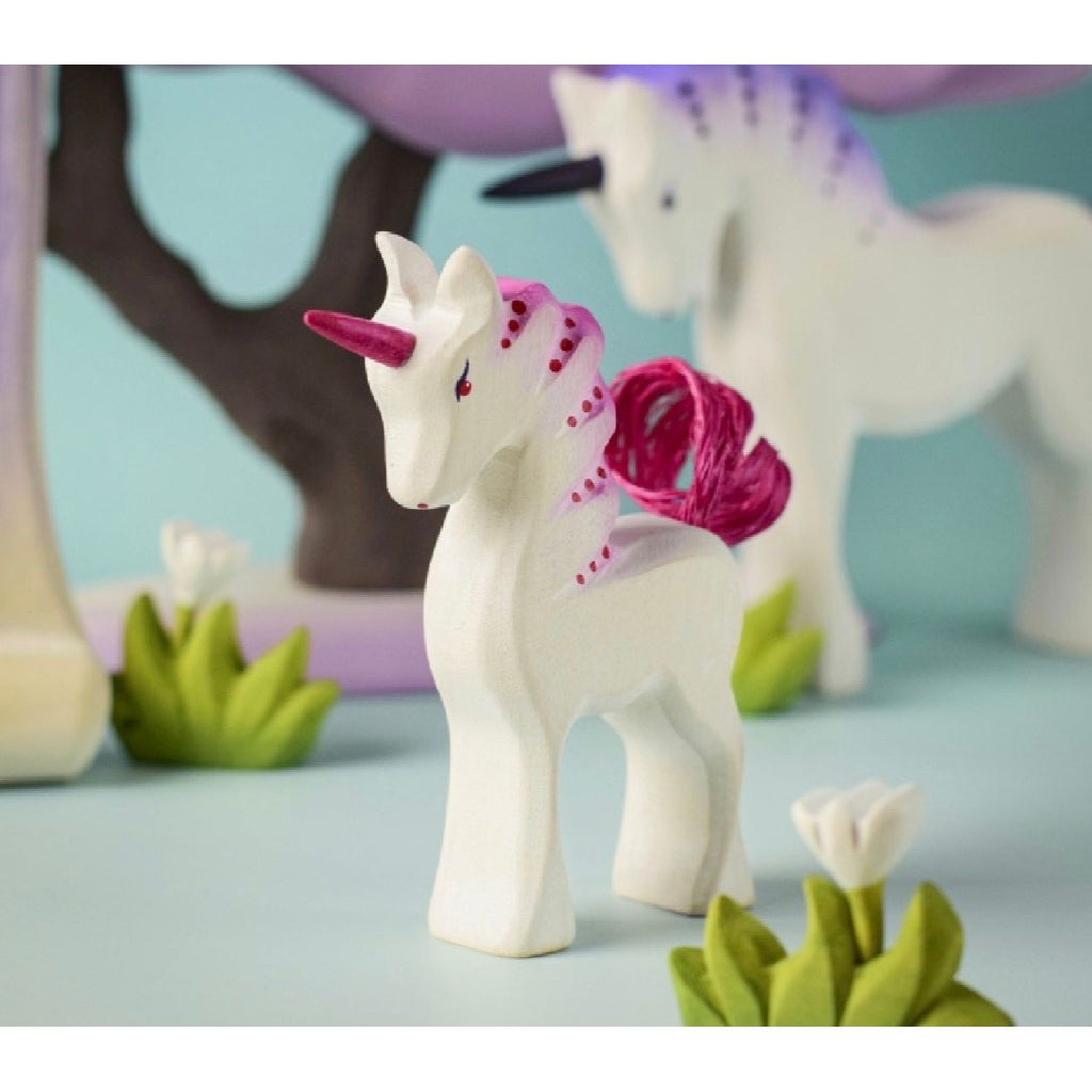 Unicorn figurine with pink mane and tail on a wooden surface