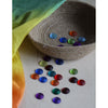 Colorful buttons on a wooden surface with a textured fabric background