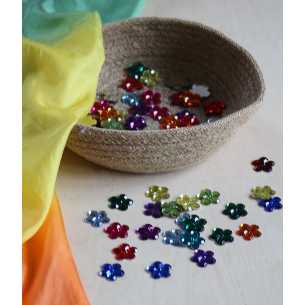 Colorful bead patterns on a cardboard sheet with rainbow fabric in the background