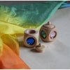 Wooden toys with colorful lenses on a white surface with multicolored fabric in the background.