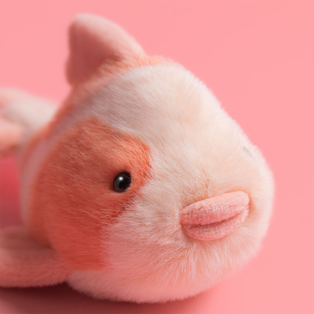 Plush fish toy with pink and white colors on a white background