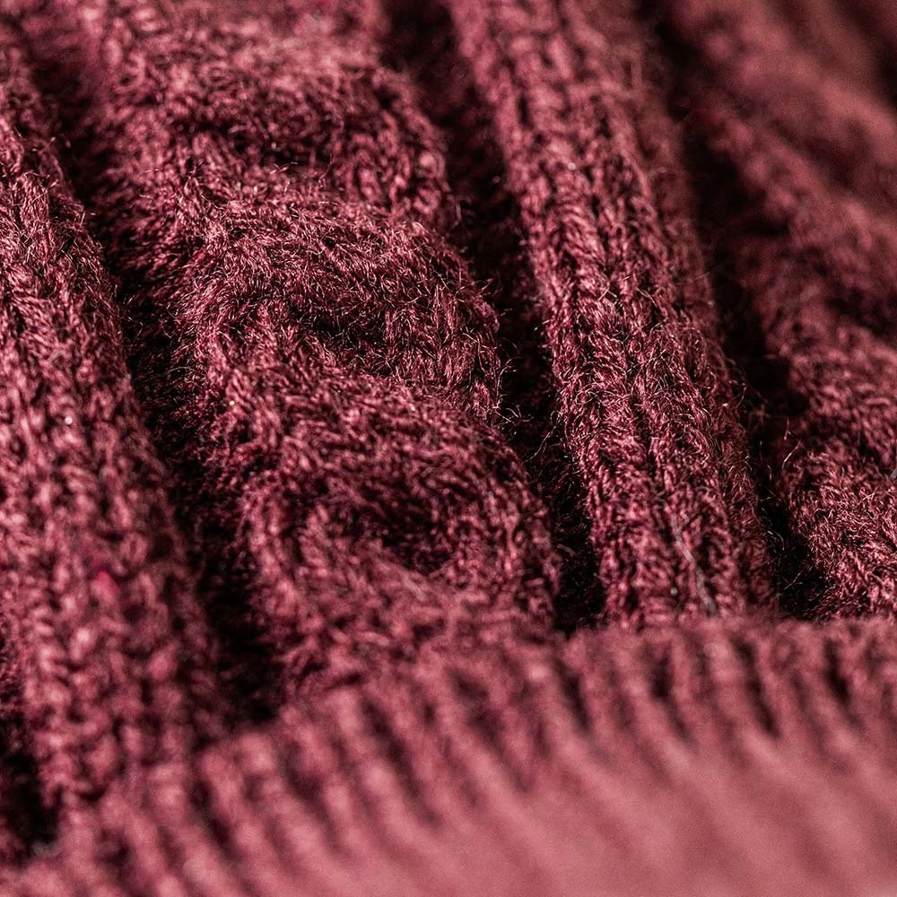 A plush West Highland terrier dog toy wearing a burgundy cable-knit sweater, set against a plain white background.