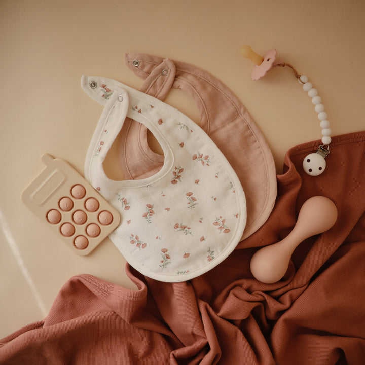 Baby bib with floral pattern and pink backside on a white background