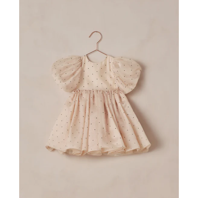 Young girl in a pink dress standing in a room with decorative elements.