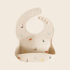 Beige baby silicone bib with dinosaur prints 