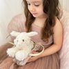 Young girl holding a white plush Maltese Puppy toy with a pink dress.