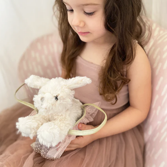 Young girl holding a white plush Maltese Puppy toy with a pink dress.