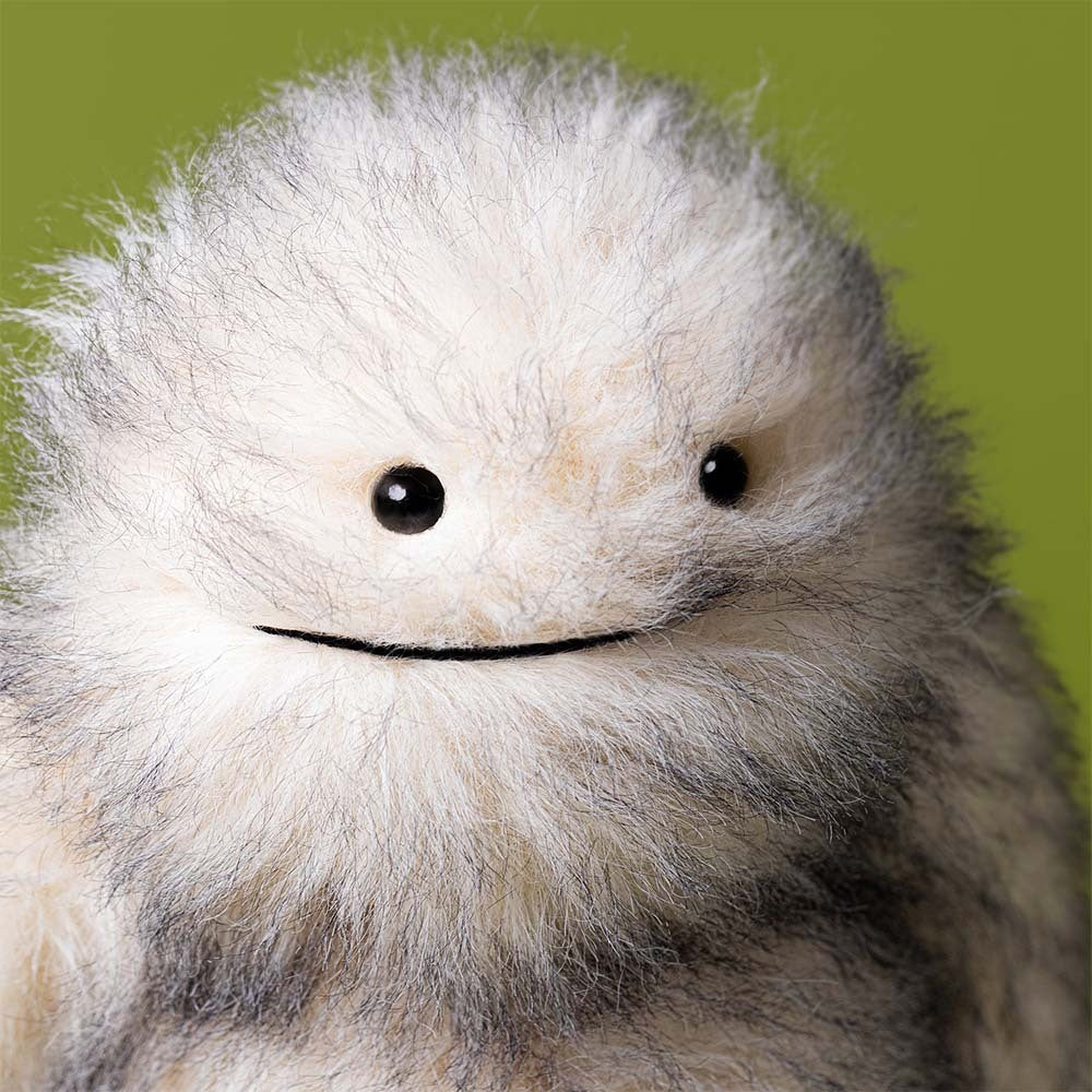 Plush toy resembling a creature with gray and white fur on a white background