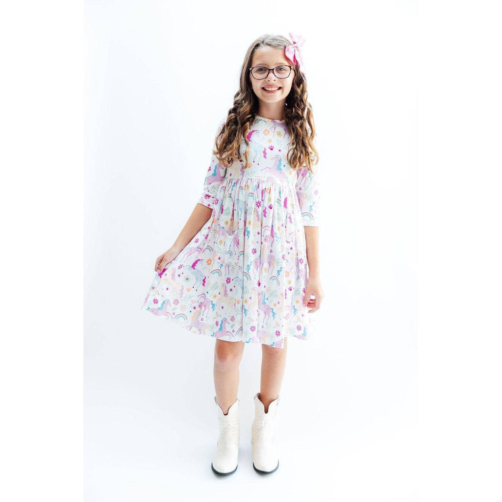 Young girl wearing a colorful dress with cartoon designs on a white background