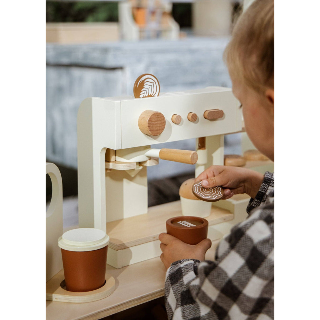 Wooden toy bakery set with pastries and cups on a light background