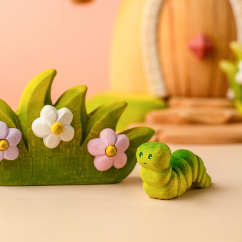 Green caterpillar toy on a wooden surface with a light blue background
