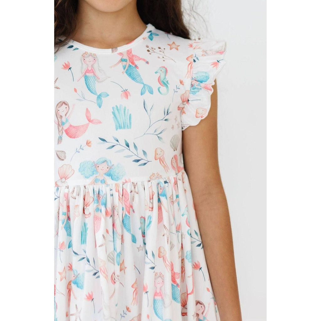 Young girl wearing a floral dress against a plain background