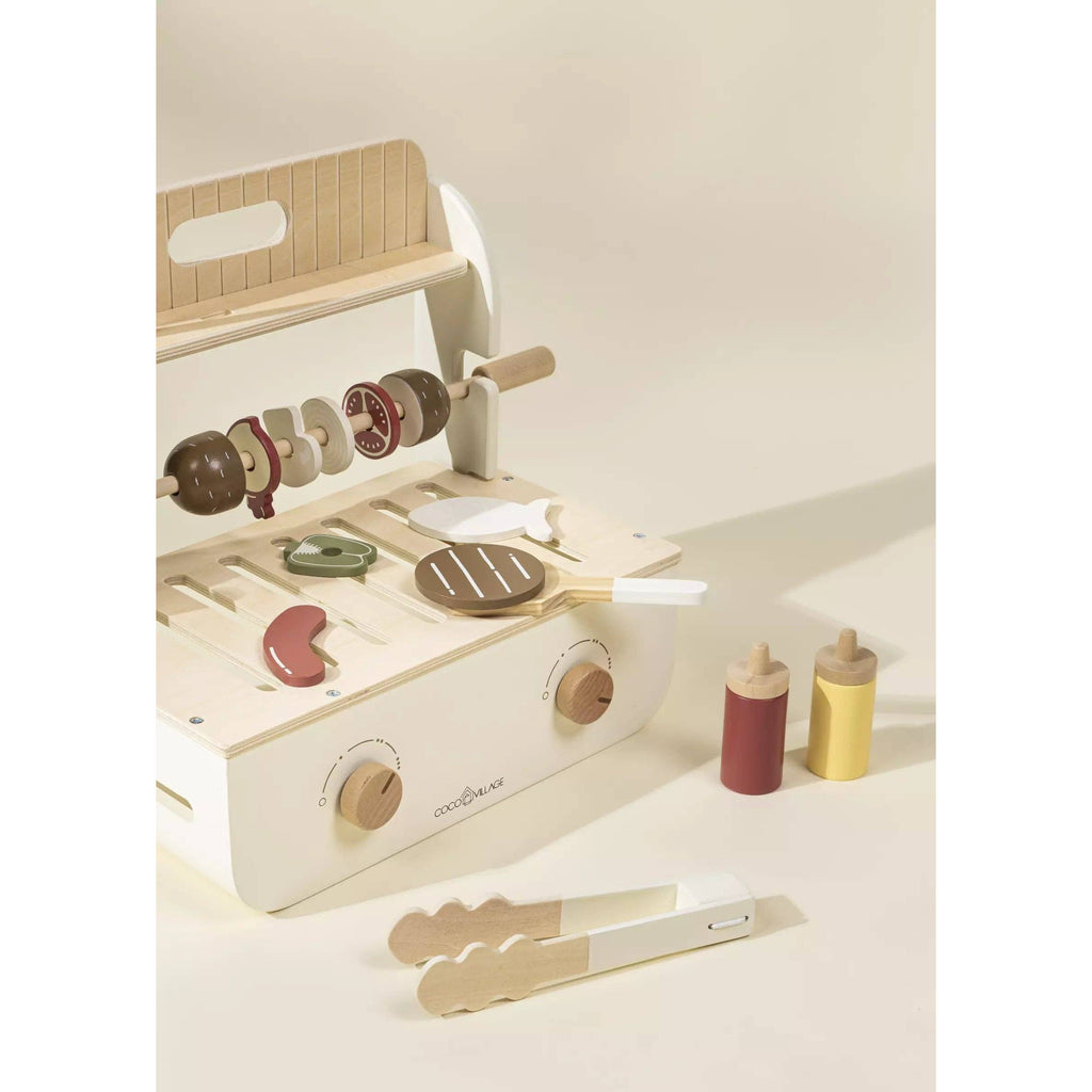 Wooden toy kitchen set with various utensils on a light background