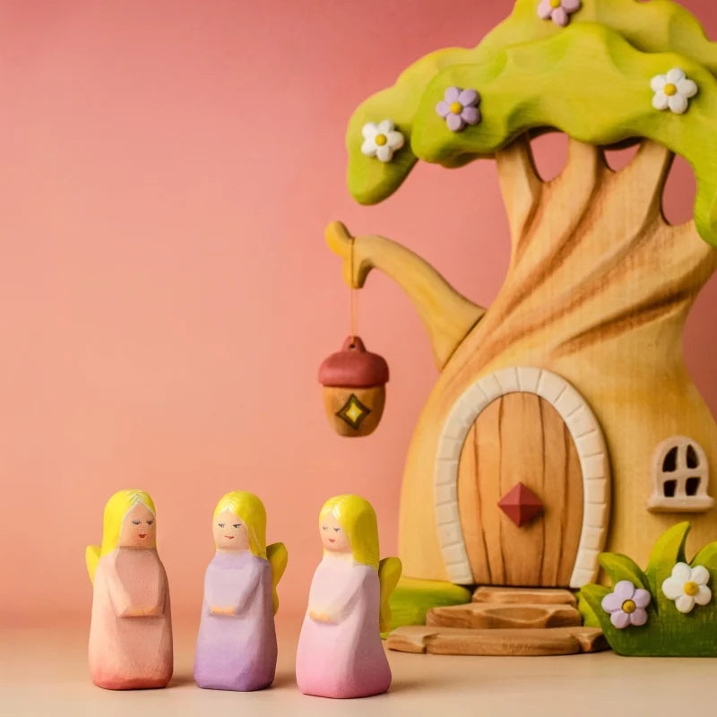 Wooden toy treehouse with three small figures on a wooden surface and light blue background