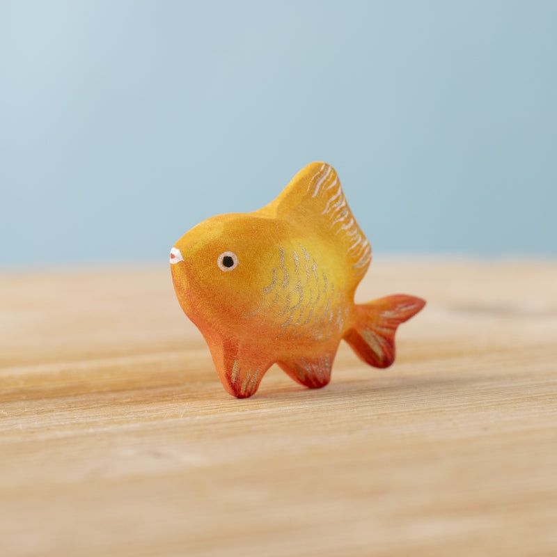 Toy fish on a sandy surface with a blue background